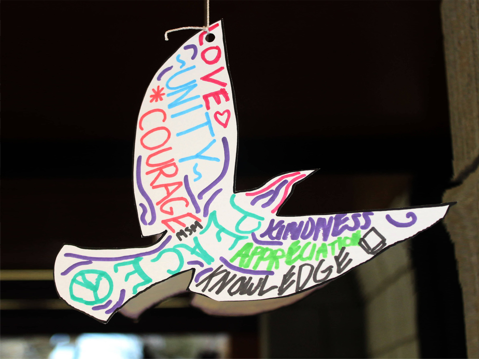 Paper dove decorated with words: Love, Unity, Courage, Kindness, Appreciation, Knowledge